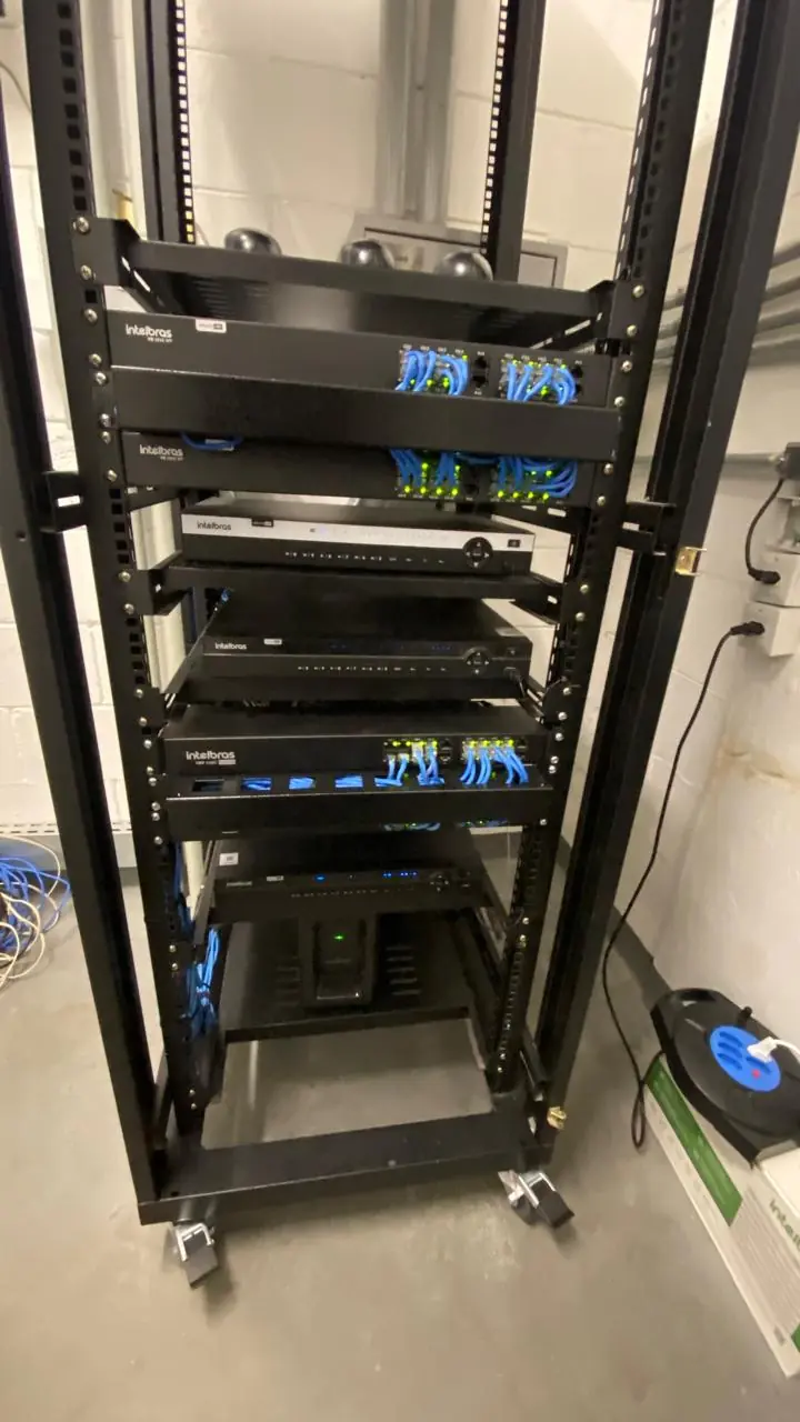 Rack com NVRs Intelbras e switches com cabos azuis organizados